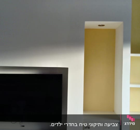 קיר צבוע בלבן וצהוב עם מדפים
